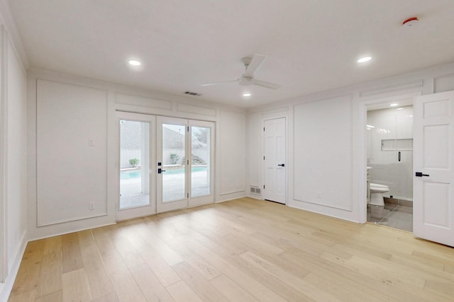 interior space with a ceiling fan, visible vents, a decorative wall, and light wood-style flooring