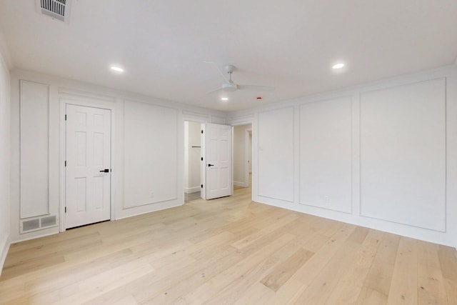 interior space with light wood-style flooring, visible vents, and a decorative wall