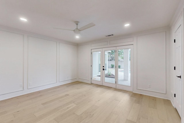 spare room with light wood-type flooring, visible vents, a decorative wall, and french doors