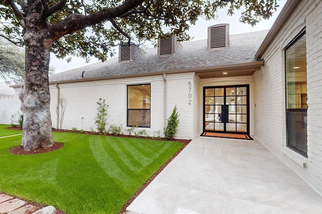 exterior space with a chimney, brick siding, a lawn, and a shingled roof