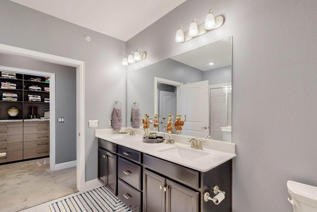 full bath featuring double vanity, toilet, baseboards, and a sink