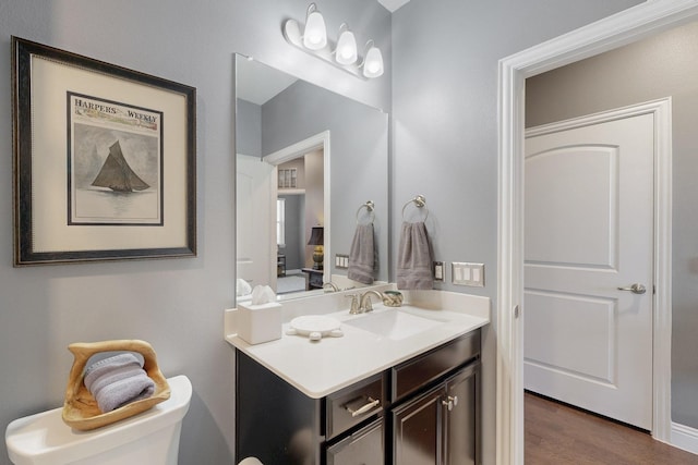 bathroom featuring toilet, vanity, and wood finished floors