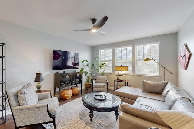 living area with baseboards, ceiling fan, and wood finished floors