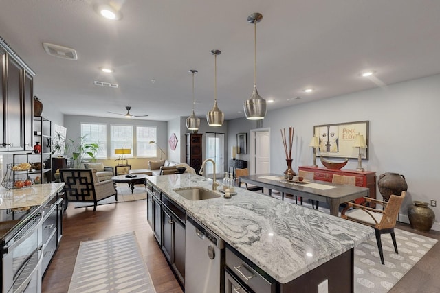 kitchen with visible vents, dark wood finished floors, an island with sink, a sink, and stainless steel dishwasher