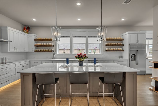 kitchen with cooktop, stainless steel fridge, open shelves, and light countertops