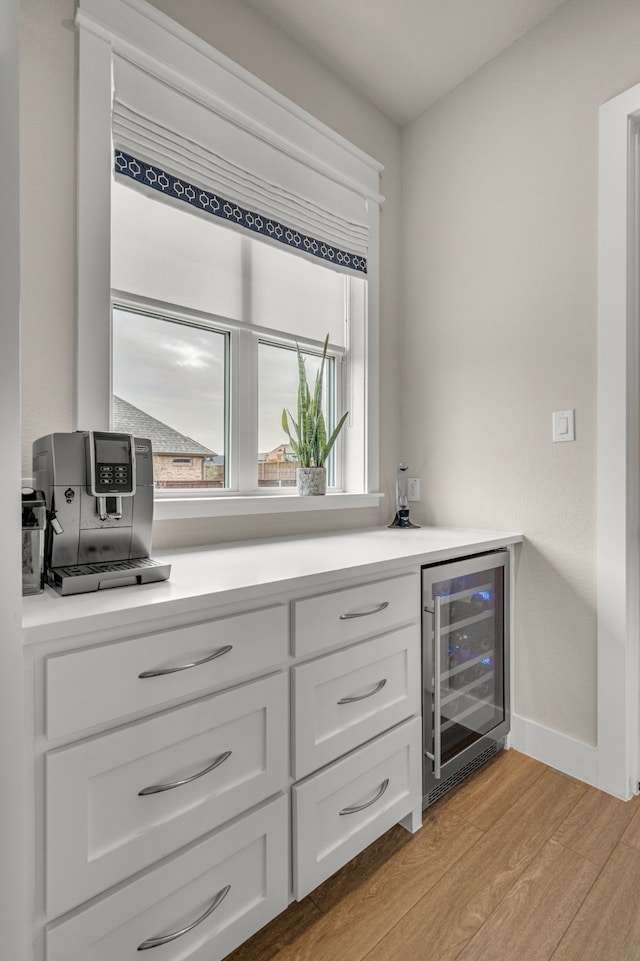 bar featuring baseboards, wine cooler, and light wood-style floors