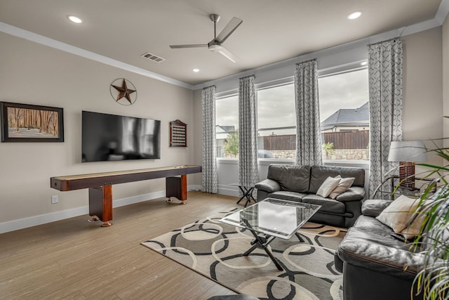 living area with light wood finished floors, visible vents, baseboards, and crown molding