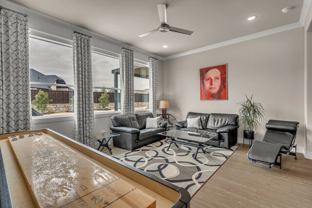 living area with recessed lighting, wood finished floors, a ceiling fan, baseboards, and ornamental molding