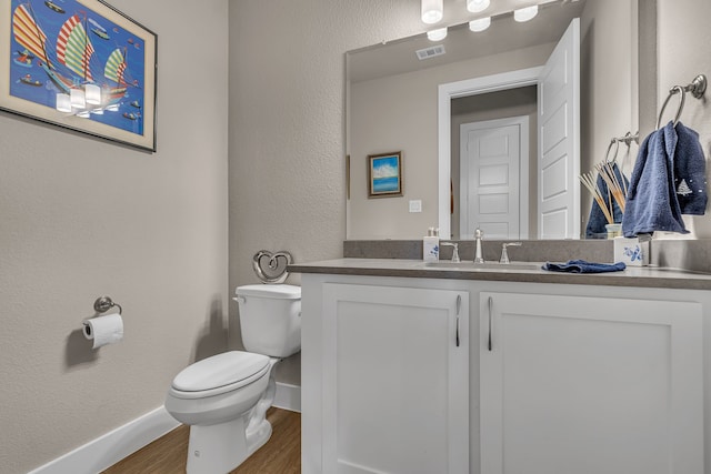 bathroom featuring toilet, wood finished floors, visible vents, vanity, and baseboards