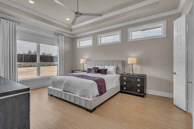 bedroom featuring light wood-type flooring, a raised ceiling, crown molding, and baseboards