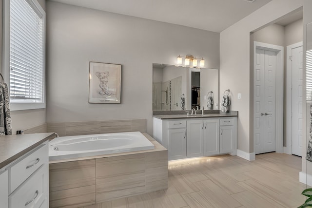 bathroom featuring a closet, vanity, a bath, and a stall shower