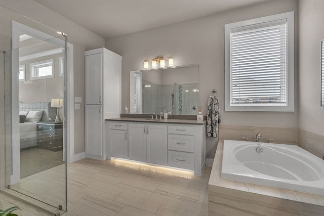 bathroom featuring a shower with shower door, a garden tub, and vanity