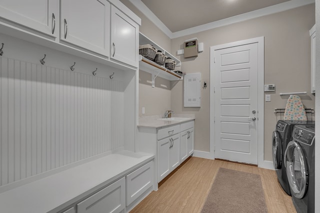 washroom with light wood-style flooring, a sink, baseboards, cabinet space, and washing machine and clothes dryer