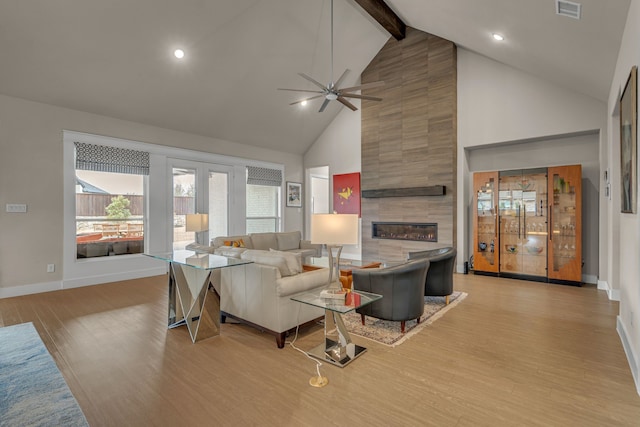 living room featuring light wood-style flooring, a fireplace, visible vents, baseboards, and beamed ceiling