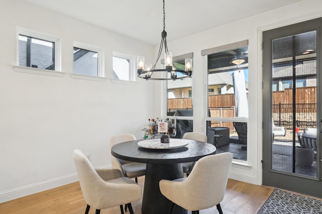 dining space with an inviting chandelier, baseboards, and wood finished floors