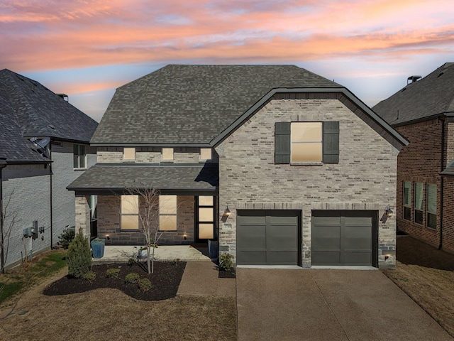 french country inspired facade with brick siding, a shingled roof, concrete driveway, an attached garage, and stone siding