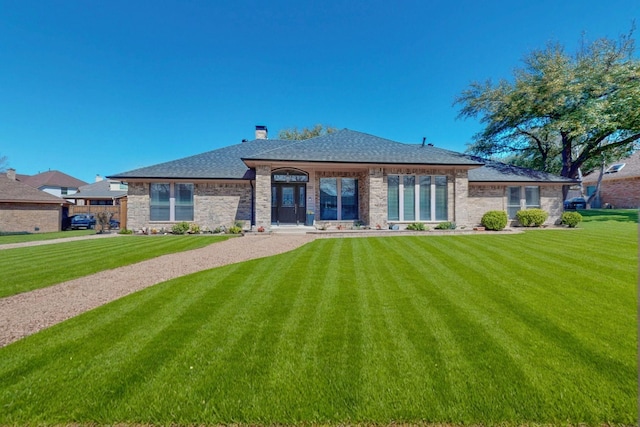 rear view of property with a lawn, brick siding, and a chimney