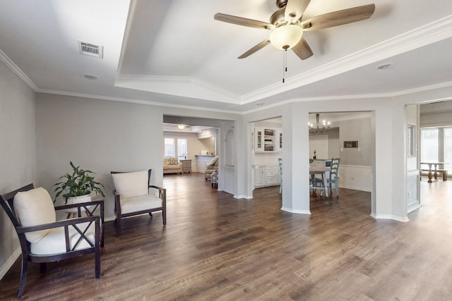 sitting room featuring wood finished floors, visible vents, a tray ceiling, ornamental molding, and ceiling fan with notable chandelier