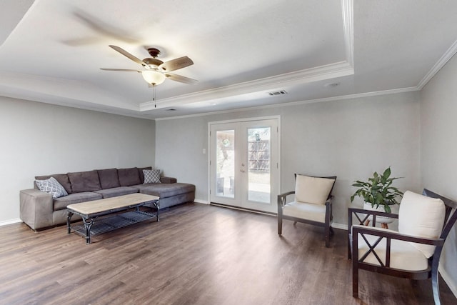 living area with crown molding, baseboards, french doors, wood finished floors, and a raised ceiling