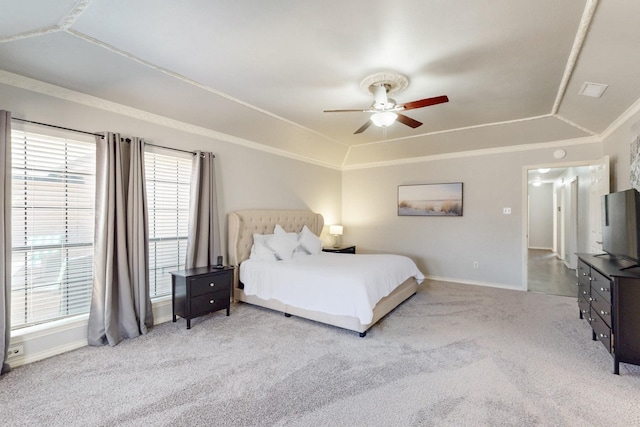 carpeted bedroom with a ceiling fan, baseboards, vaulted ceiling, crown molding, and a raised ceiling