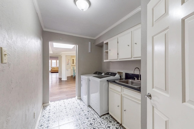 washroom with a sink, washing machine and dryer, cabinet space, crown molding, and baseboards