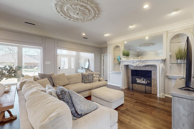 living area featuring visible vents, dark wood-style flooring, crown molding, and a decorative wall