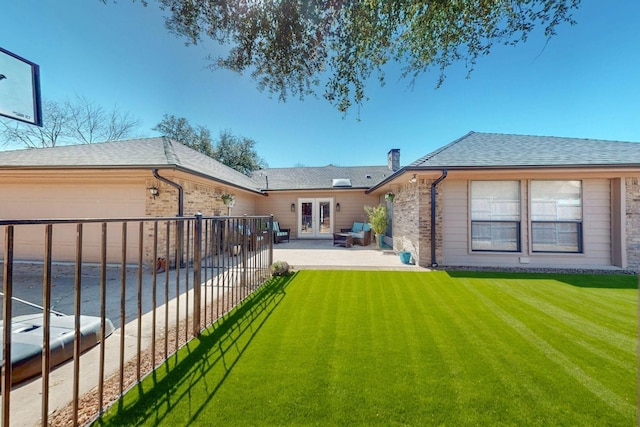 back of house featuring driveway, a yard, a chimney, french doors, and a garage