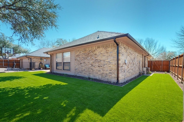 rear view of property featuring brick siding, central AC unit, a fenced backyard, and a lawn