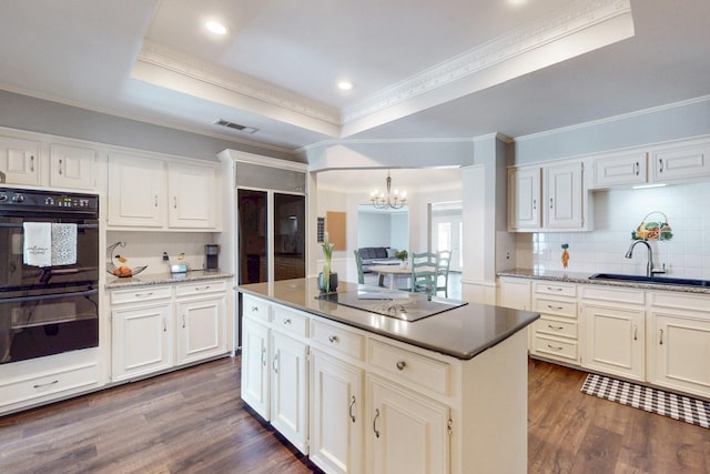 kitchen with visible vents, a sink, a tray ceiling, black appliances, and dark wood-style flooring