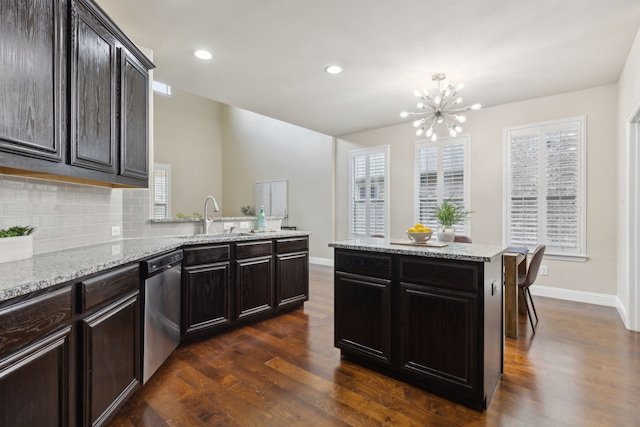 kitchen with backsplash, stainless steel dishwasher, dark wood-type flooring, a sink, and baseboards