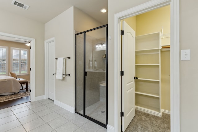 ensuite bathroom with a walk in closet, a shower stall, visible vents, and tile patterned floors