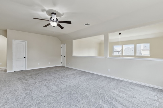 carpeted spare room featuring lofted ceiling, ceiling fan, visible vents, and baseboards