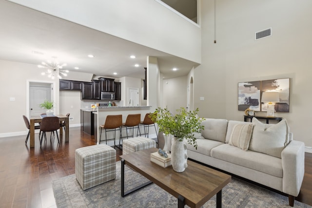 living area with baseboards, arched walkways, dark wood-style floors, a chandelier, and recessed lighting