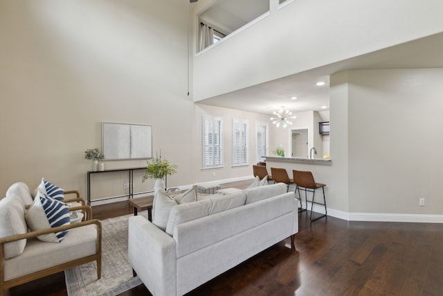 living area featuring baseboards, a towering ceiling, dark wood-style floors, a chandelier, and recessed lighting