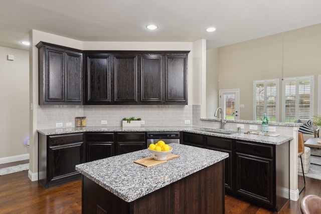 kitchen featuring tasteful backsplash, a sink, a peninsula, and dark wood-style floors