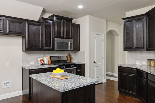 kitchen featuring light stone countertops, baseboards, stainless steel appliances, and dark wood finished floors