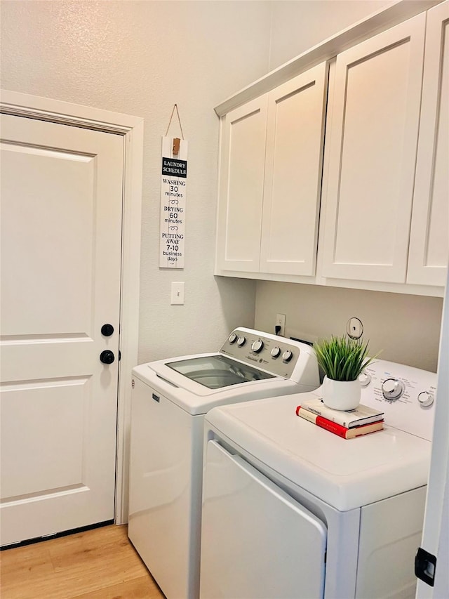 washroom with cabinet space, light wood-style flooring, and washing machine and clothes dryer