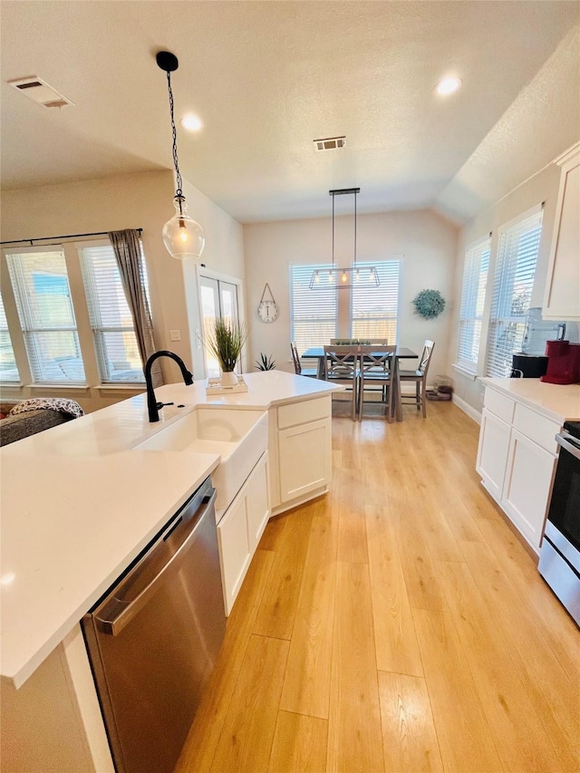 kitchen featuring light wood-style flooring, stainless steel appliances, a sink, visible vents, and hanging light fixtures