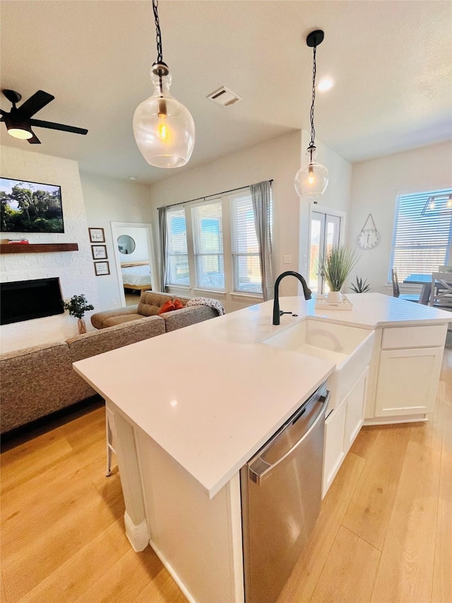 kitchen with a sink, light wood finished floors, open floor plan, and stainless steel dishwasher