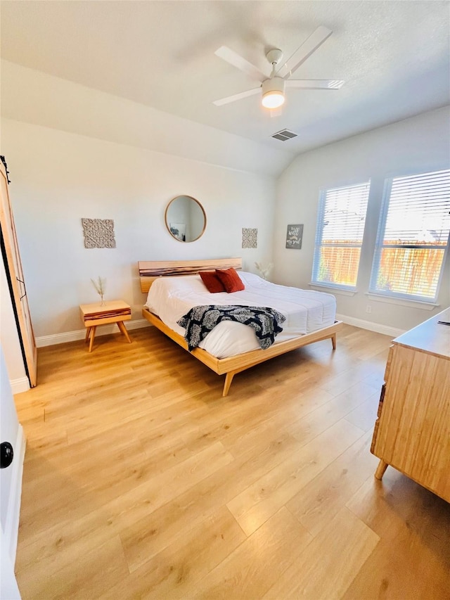 bedroom featuring lofted ceiling, a ceiling fan, baseboards, visible vents, and light wood-style floors