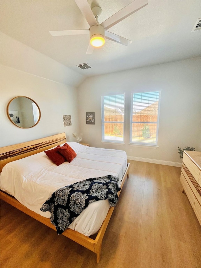 bedroom featuring light wood-style floors, lofted ceiling, visible vents, and ceiling fan