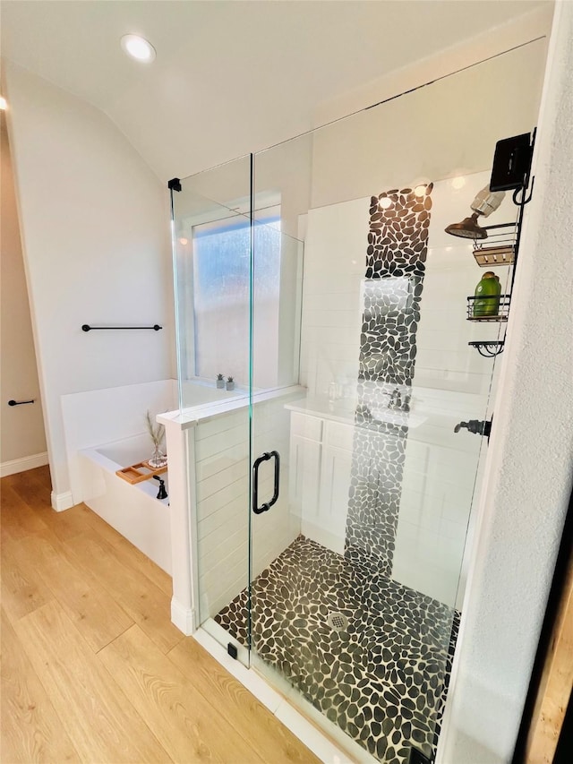 full bathroom featuring a stall shower, lofted ceiling, wood finished floors, a bath, and recessed lighting