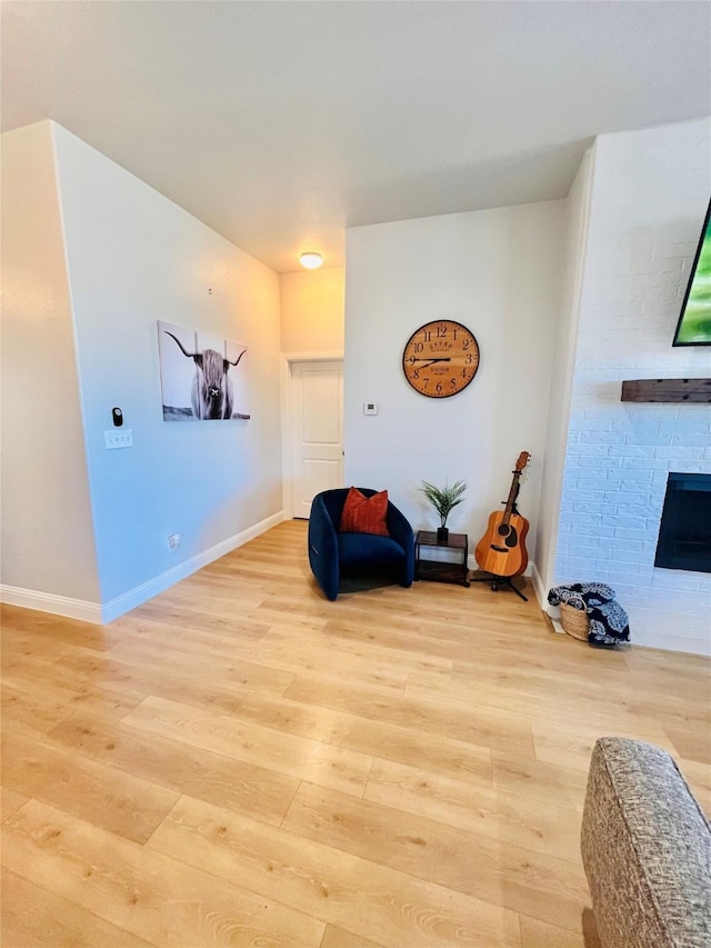 sitting room featuring light wood finished floors, baseboards, and a large fireplace