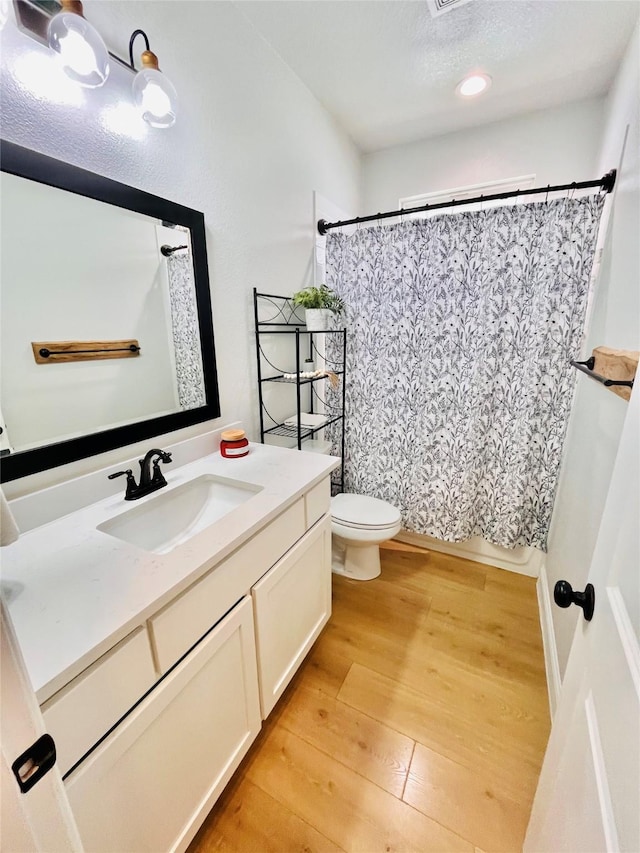 full bathroom with curtained shower, vanity, toilet, and wood finished floors