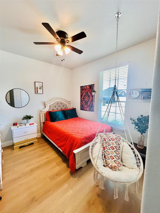 bedroom featuring ceiling fan, baseboards, and wood finished floors