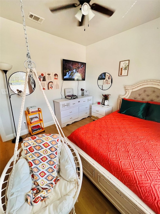 bedroom featuring wood finished floors, visible vents, and a ceiling fan