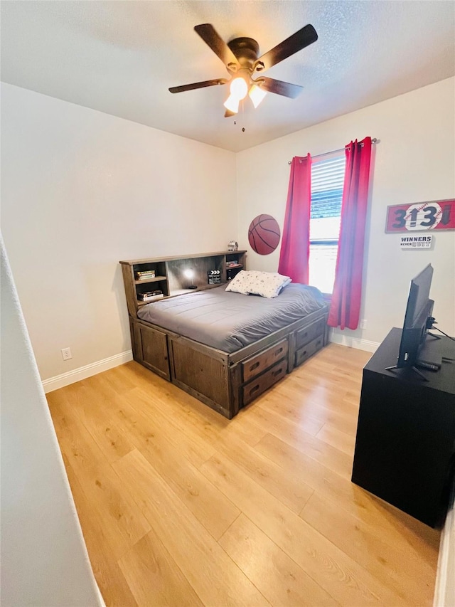 bedroom with a textured ceiling, light wood-type flooring, a ceiling fan, and baseboards