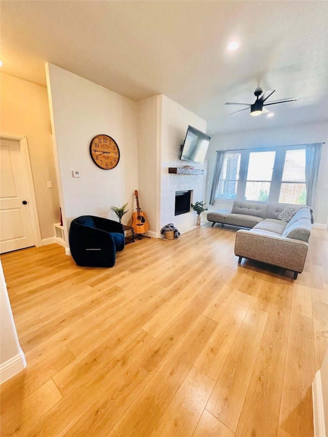 living room featuring baseboards, a fireplace, hardwood / wood-style flooring, and a ceiling fan