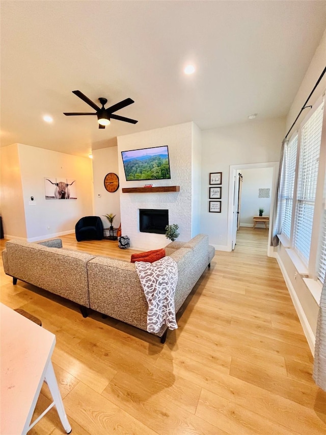 living room with a glass covered fireplace, light wood-style flooring, and recessed lighting