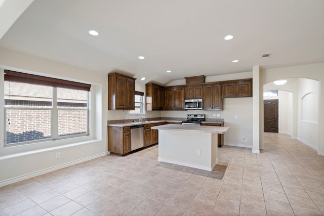 kitchen with arched walkways, a center island, light countertops, visible vents, and appliances with stainless steel finishes